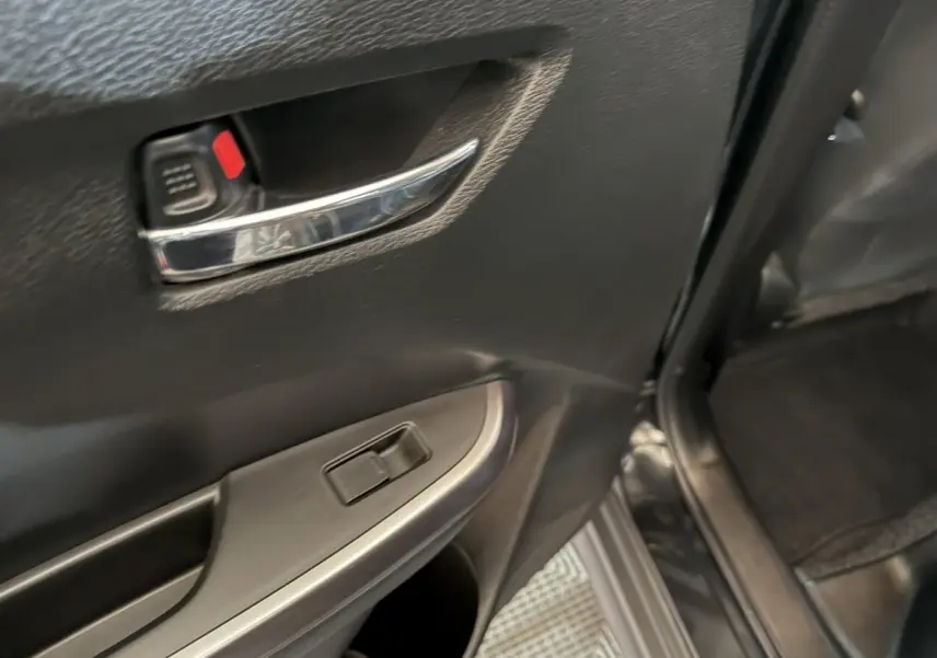 Vue rapprochée de la porte arrière droite noire du Suzuki Vitara 1.5 Dualjet hybrid STYLE avec poignée chromée et commande de vitre.