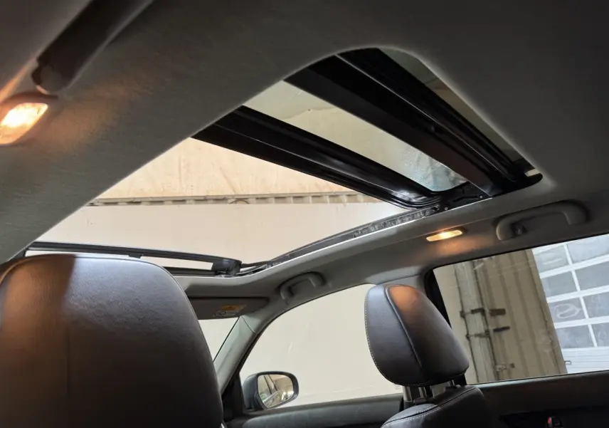 Vue intérieure du toit ouvrant panoramique électrique du Suzuki Vitara noir, avec appuis-tête en cuir visibles côté droit.