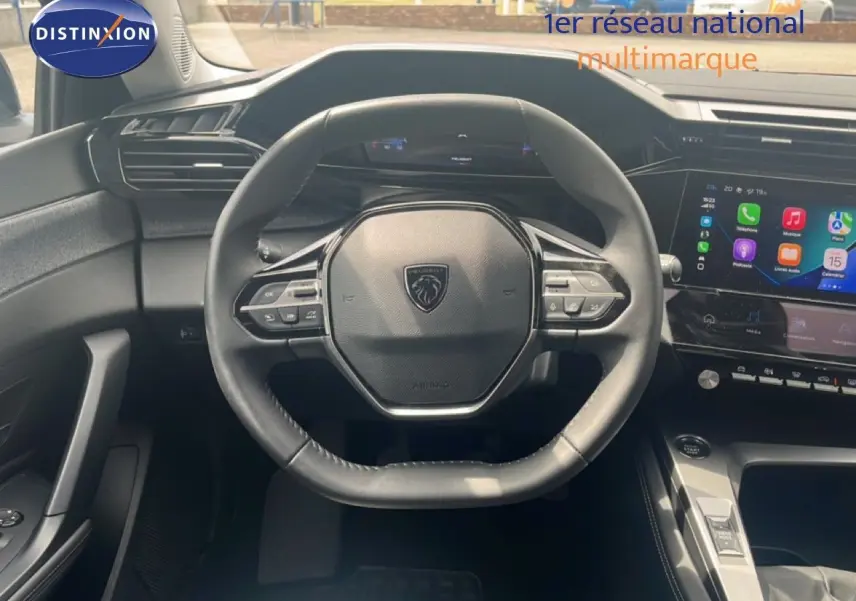 Vue intérieure centrée sur le volant cuir noir de la Peugeot 308 2024 avec écran tactile et tableau de bord digital.