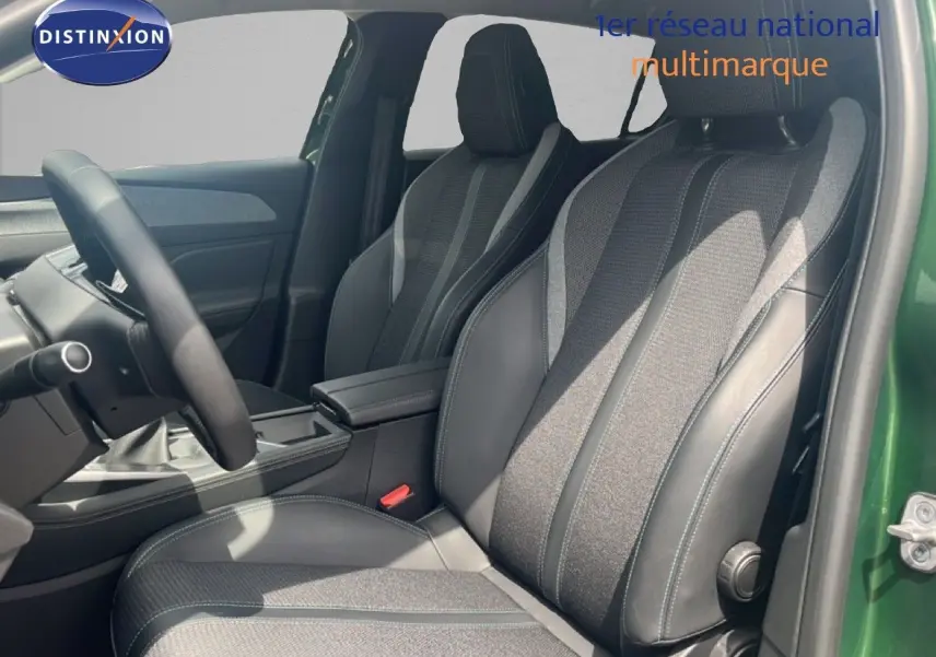 Vue intérieure côté conducteur de la Peugeot 308 2024 vert olivine, sièges en tissu et cuir gris noir, volant multifonction.