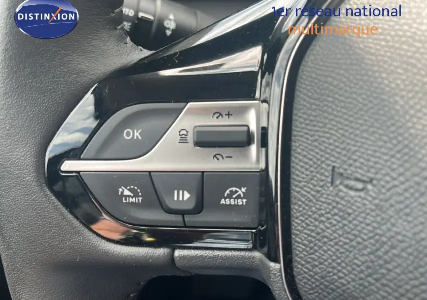 Gros plan sur les commandes de régulateur et limiteur de vitesse au volant d’une Peugeot 308 vert olivine métal.