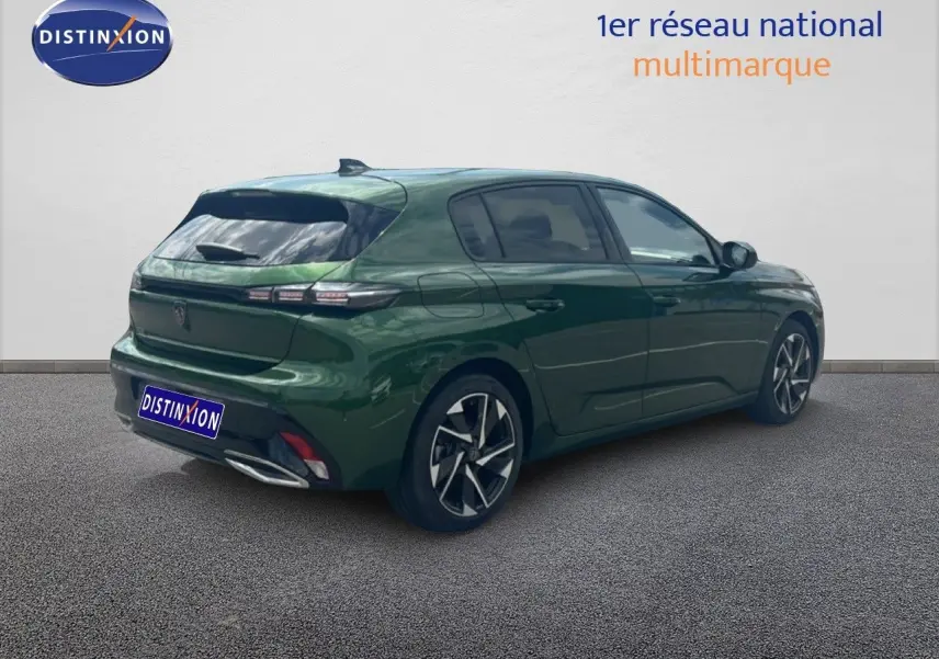 Vue 3/4 arrière droite d'une Peugeot 308 2024 vert olivine métallisé avec jantes bi-ton et feux arrière LED distinctifs.