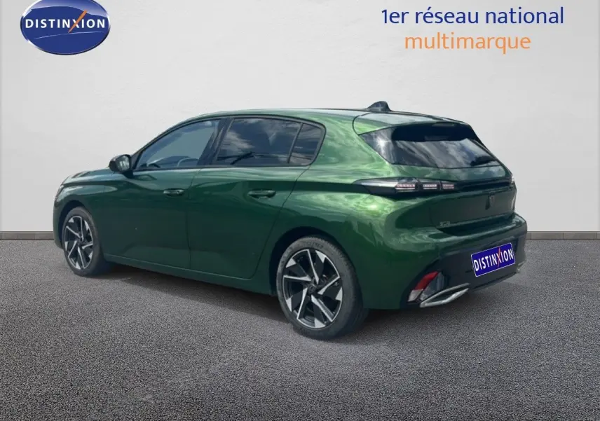 Vue 3/4 arrière droite d'une Peugeot 308 2024 vert olivine métallisé avec jantes alliage et vitres teintées.