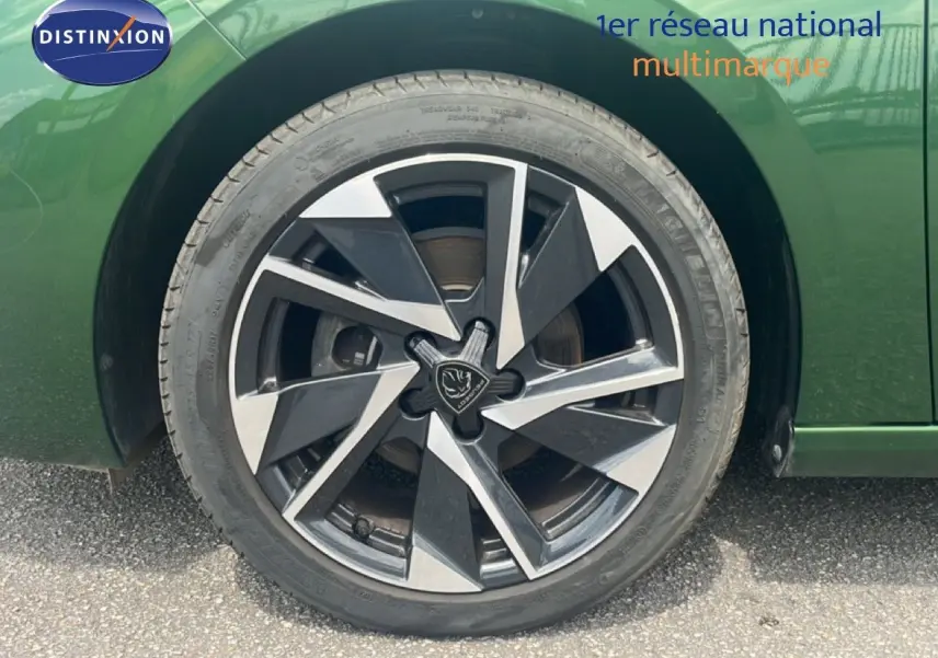 Gros plan sur la roue avant gauche de la Peugeot 308 2024 vert olivine métal avec jante alliage bicolore distinctive.