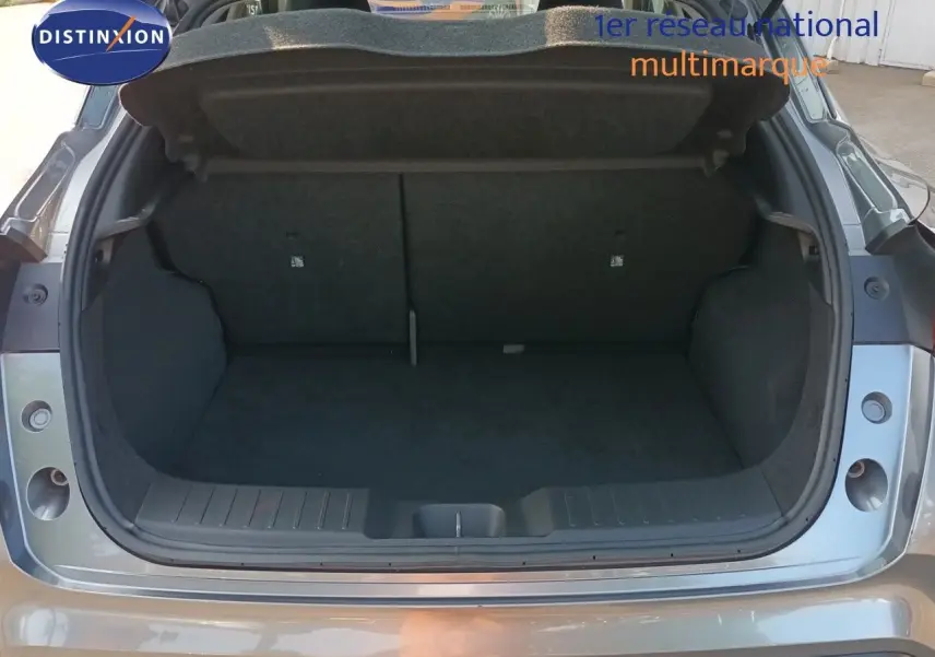 Coffre ouvert vu de l'arrière d'un Nissan Juke 2025 gris squale métal, montrant l'espace de chargement vide.