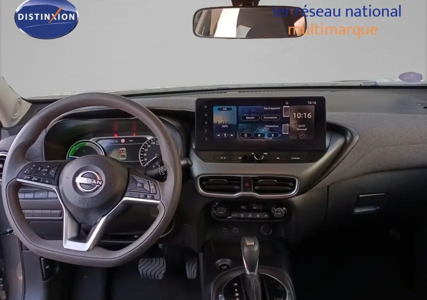 Vue intérieure frontale du tableau de bord du Nissan Juke Hybrid 2025 avec écran tactile et volant multifonction noir.