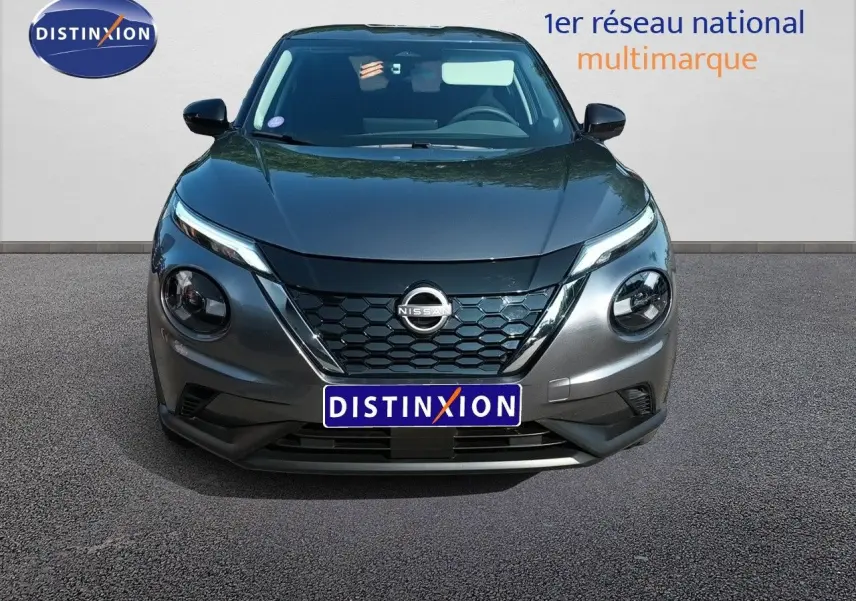 Vue frontale d'un Nissan Juke hybride gris squale métal avec calandre hexagonale et phares ronds distinctifs.