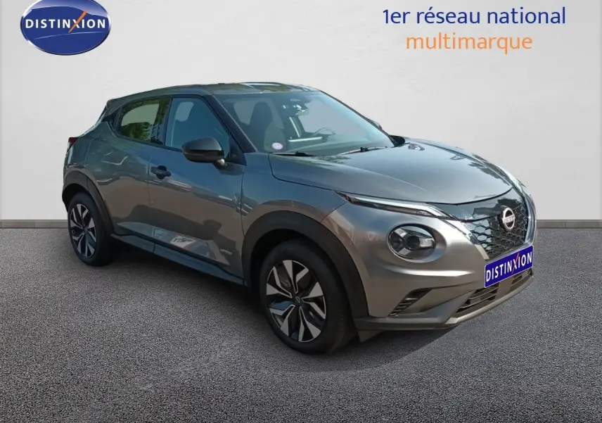 Nissan Juke Hybrid gris squale métal en 3/4 avant droit, avec calandre distinctive et jantes stylisées.