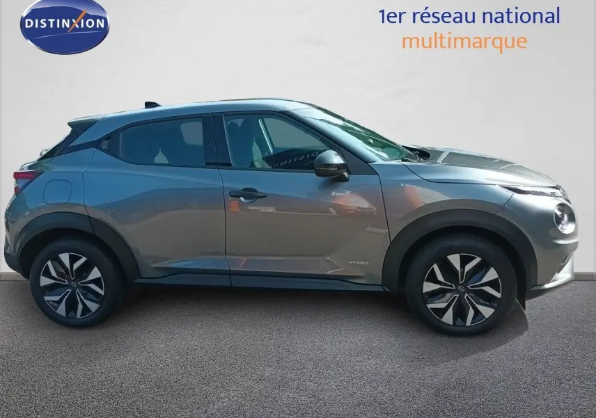Profil latéral droit du Nissan Juke Hybrid 143ch gris squale métal avec jantes distinctives et détails noirs.