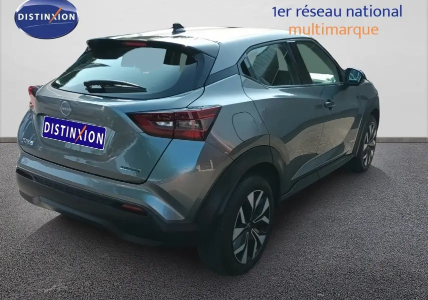 Vue 3/4 arrière droite du Nissan Juke Hybrid 143ch Acenta gris squale métal avec jantes distinctives et feux arrière LED.