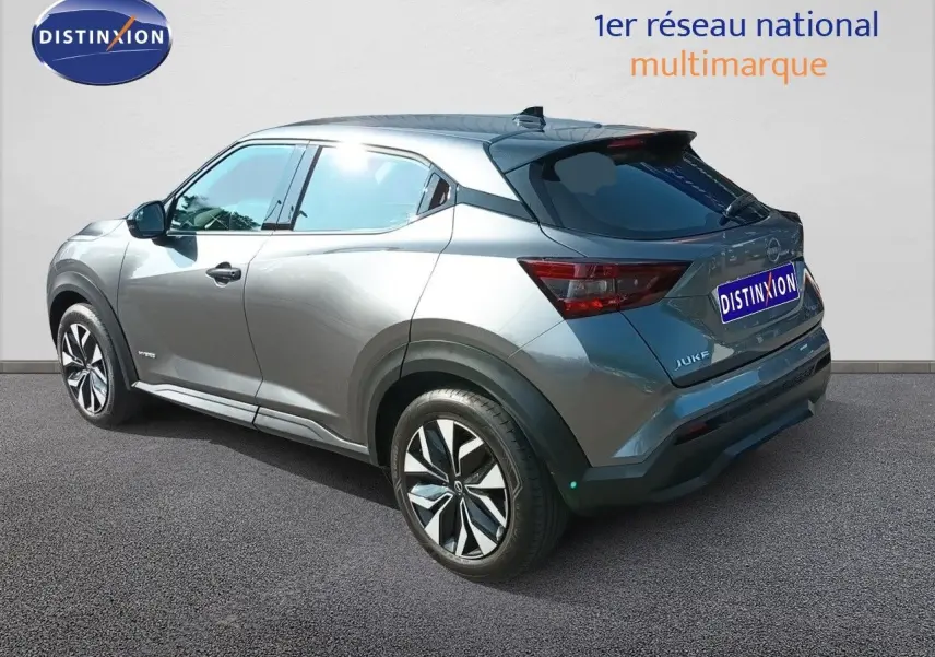 Nissan Juke Hybrid gris squale métal, vue 3/4 arrière droit, avec jantes alliage et vitres teintées.