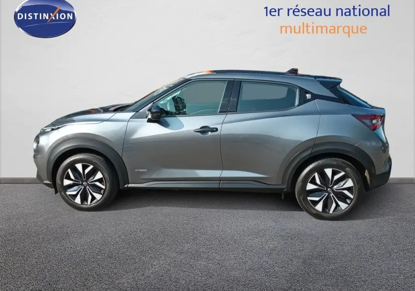 Profil droit du Nissan Juke hybride 2025 gris squale métal avec jantes noires et détails noirs contrastants.