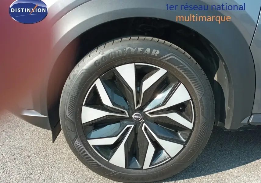 Gros plan sur la roue avant droite du Nissan Juke 2025 gris squale métal avec jante alliage noire et argentée.