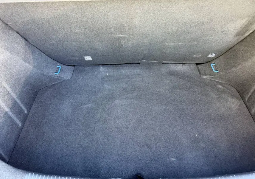 Coffre spacieux de la MG3 1.5 Hybrid+ 195ch Comfort 2024, revêtement tissu noir avec crochets bleus visibles.