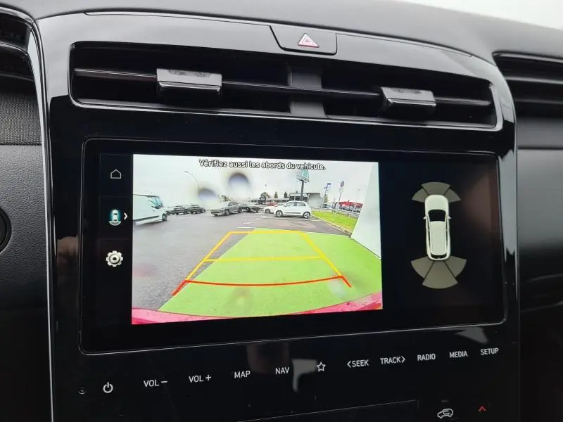 Écran tactile intérieur du Hyundai Tucson IV montrant la caméra de recul avec lignes de guidage en stationnement.