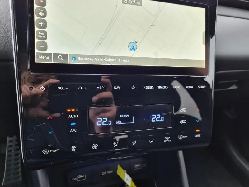 Gros plan sur la console centrale du Hyundai Tucson IV blanc polaire, affichant la climatisation automatique bi-zone et l'écran tactile de navigation.