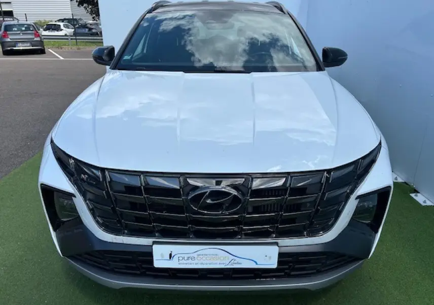 Vue avant d'un Hyundai Tucson blanc polaire avec toit noir et calandre noire au design marqué N-Line.
