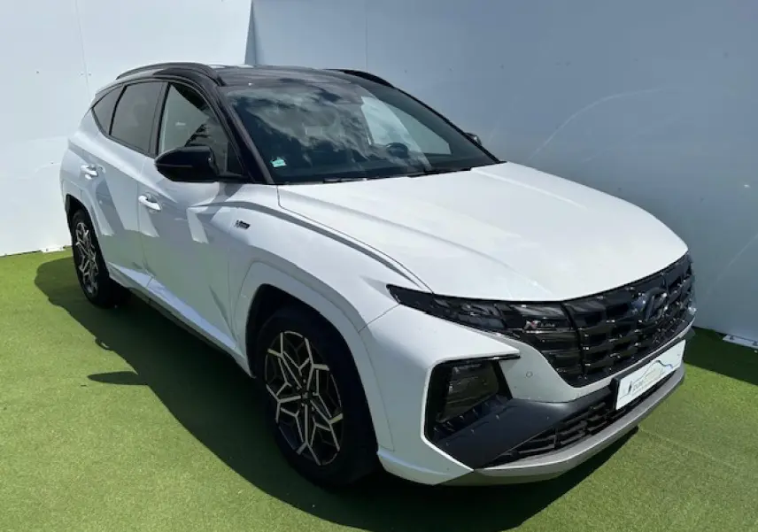 Vue 3/4 avant gauche du Hyundai Tucson blanc polaire avec toit noir et calandre noire distinctive N-LINE.