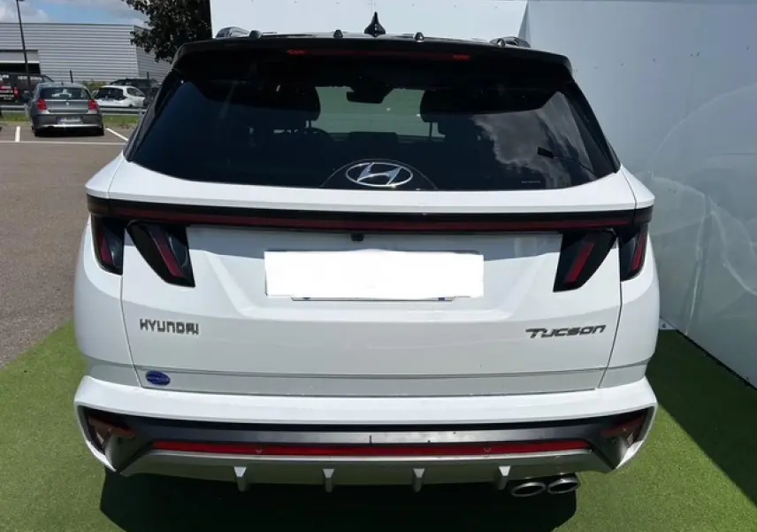 Vue arrière d'un Hyundai Tucson blanc polaire avec toit noir, feux arrière LED et double sortie d'échappement chromée.