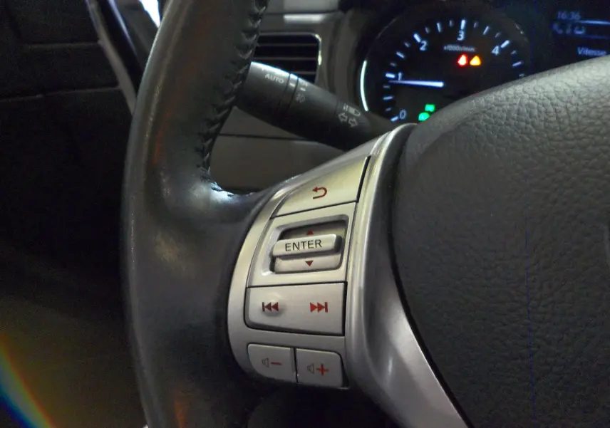 Gros plan sur la partie gauche du volant en cuir noir d'une Nissan Pulsar 2019, avec commandes audio intégrées.