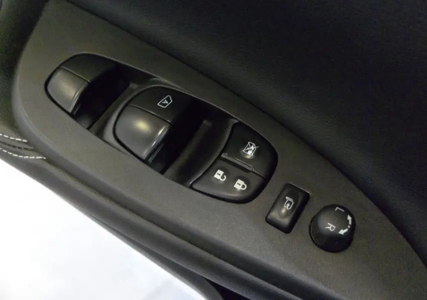 Gros plan sur les commandes de lève-vitres et rétroviseurs électriques côté conducteur d'une Nissan Pulsar gris glacier 2019.