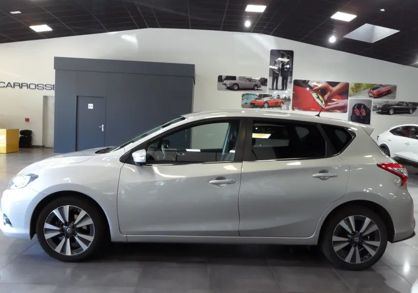 Profil côté gauche d'une Nissan Pulsar gris glacier 2019 en intérieur, avec jantes alliage et vitres teintées.