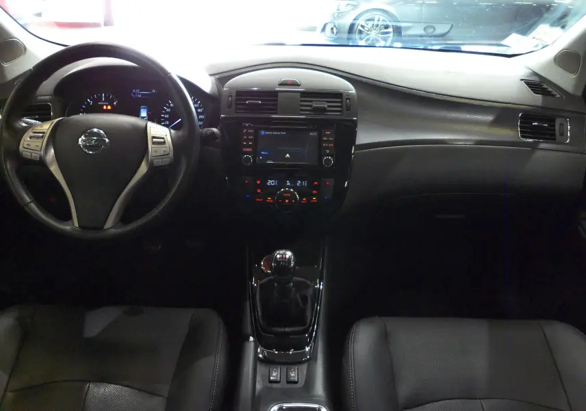 Intérieur noir de la Nissan Pulsar 2019, vue frontale du tableau de bord avec volant et levier de vitesses manuel.