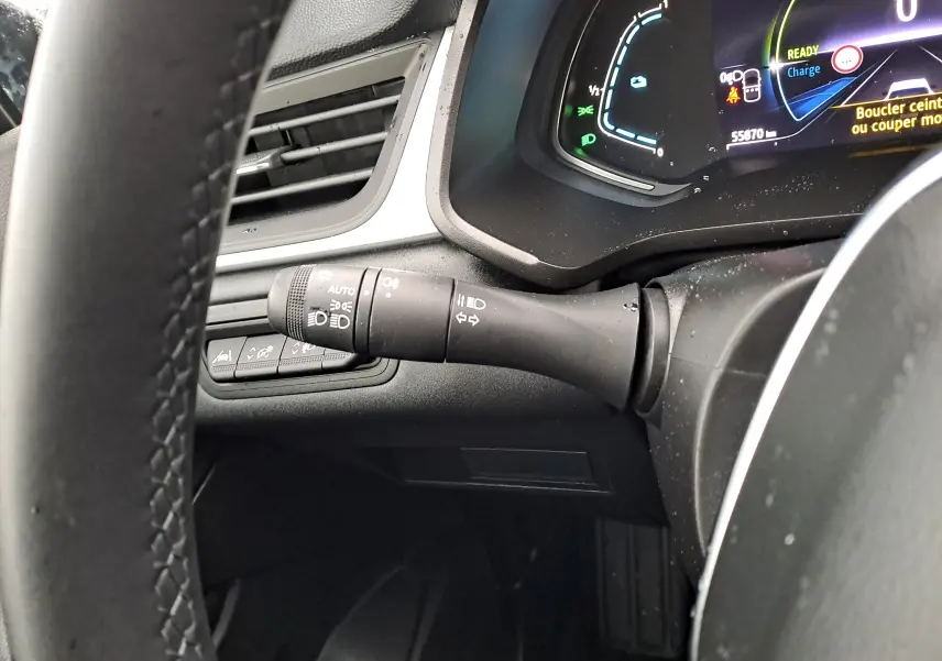 Gros plan sur la commande des feux et clignotants à gauche du volant du Renault Captur gris Cassiopée, tableau de bord numérique visible.