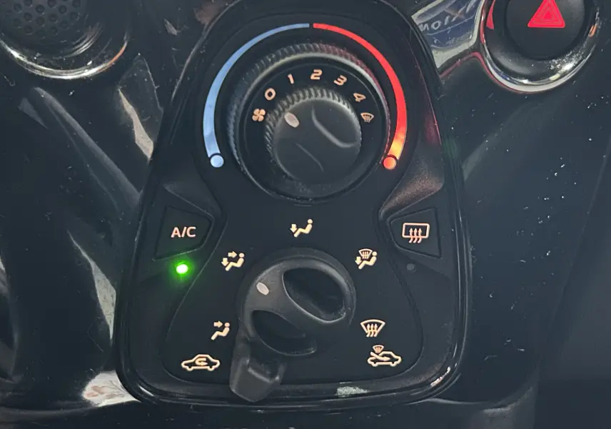 Gros plan sur les commandes de climatisation avec bouton A/C allumé dans une Citroën C1 rouge de 2019.