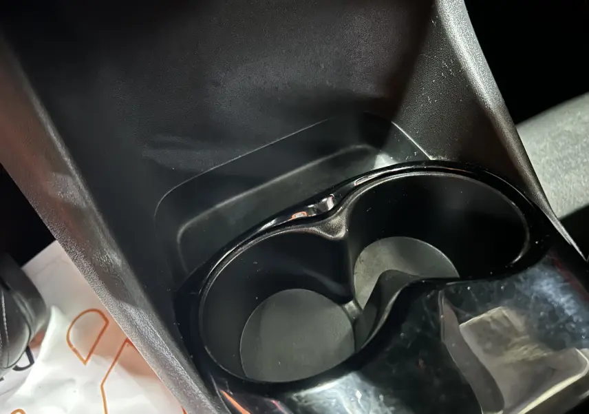 Gros plan sur les porte-gobelets noirs au centre de la console intérieure d'une Citroën C1 rouge de 2019.