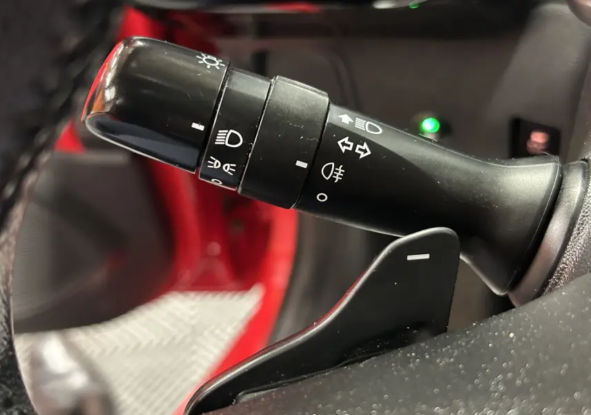 Gros plan sur la commande des feux et clignotants à gauche du volant d'une Citroën C1 rouge de 2019.