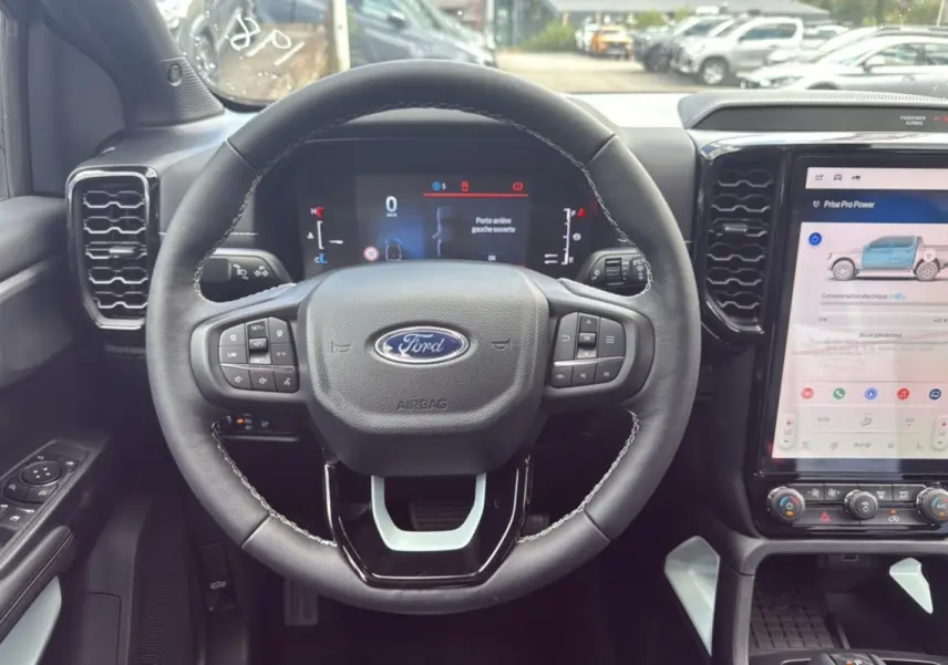 Vue intérieure centrée sur le volant du Ford Ranger 2025 noir agate avec écran tactile et commandes au volant.