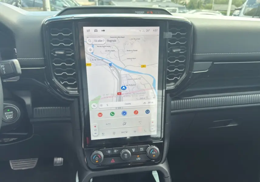 Vue rapprochée de l'écran tactile central et tableau de bord noir du Ford Ranger 2025 hybride, avec navigation affichée.