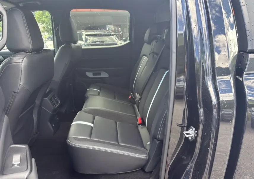 Vue intérieure côté gauche sur les sièges arrière en cuir noir du Ford Ranger 2025 noir agate avec détails blancs.