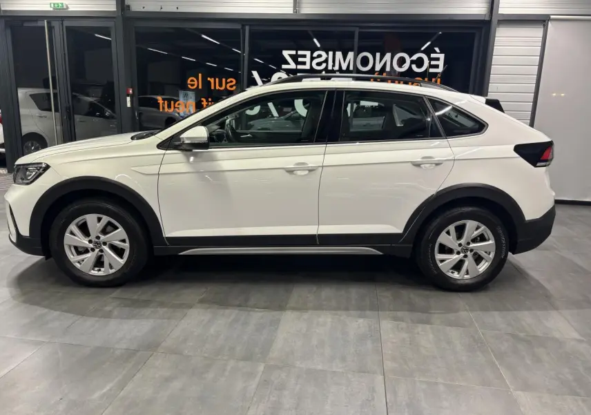 Vue de profil côté gauche d’un Volkswagen Taigo blanc, avec jantes alliage et protections noires sur les bas de caisse.