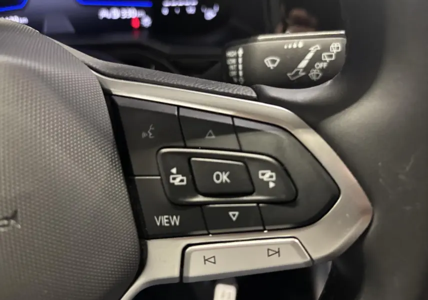 Gros plan sur les commandes du volant cuir multifonctions côté gauche du Volkswagen Taigo blanc 2023.