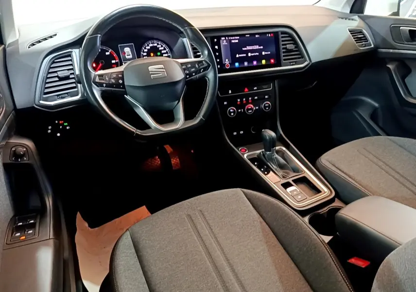 Vue intérieure avant du SEAT Ateca 2022, volant cuir alu multifonctions et écran tactile central allumé.