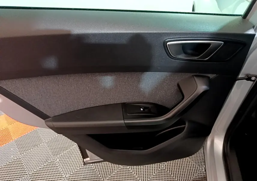 Vue intérieure côté gauche de la porte avant d’un SEAT Ateca gris clair, avec poignée noire et panneau tissu gris.