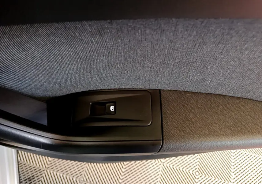 Gros plan sur le bouton de verrouillage de porte côté conducteur du SEAT Ateca gris clair, intérieur tissu et plastique noir.