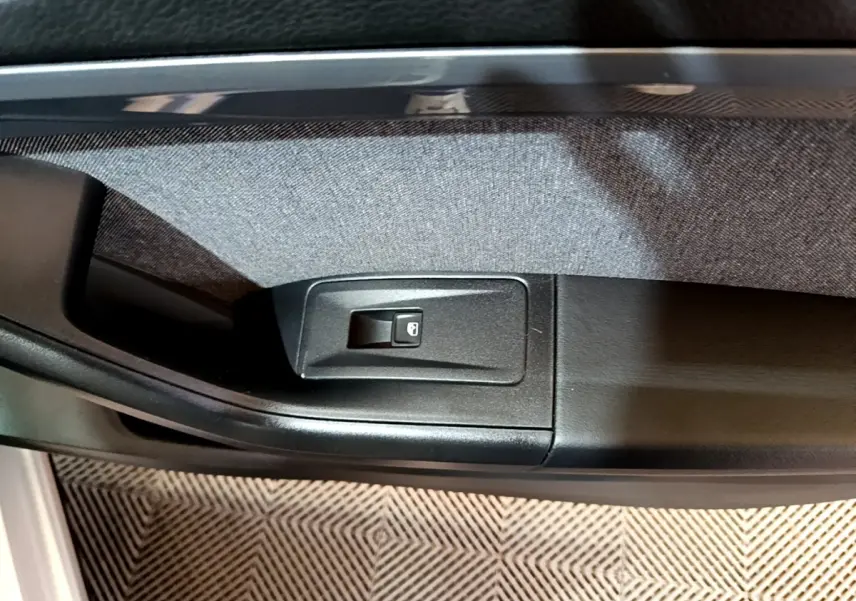 Gros plan sur le bouton de verrouillage des portes côté intérieur d'une SEAT Ateca gris clair.
