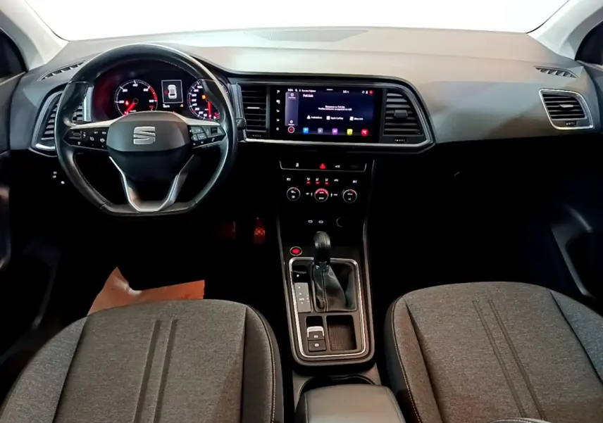 Vue intérieure avant du tableau de bord et volant cuir noir du SEAT Ateca 2022 avec écran tactile central allumé.