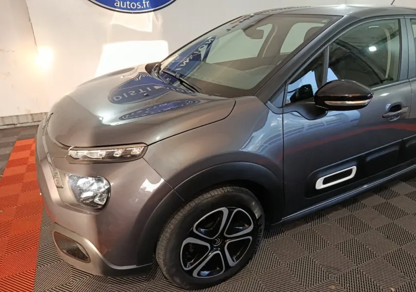 Vue 3/4 avant droit d'une Citroën C3 gris foncé avec phares LED et protections latérales noires.
