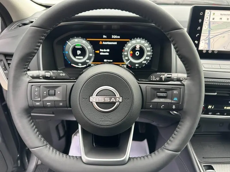 Vue centrée sur le volant du Nissan Qashqai Hybrid e-POWER 2025, avec tableau de bord numérique et écran tactile visible.
