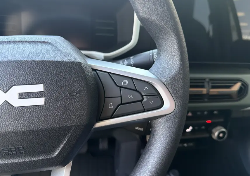 Gros plan sur le volant noir du Dacia Spring 65 Extreme 2026, avec commandes multifonctions et tableau de bord partiellement visible.
