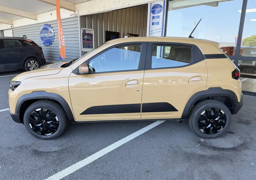 Vue latérale droite d'une Dacia Spring 65 Extreme beige Safari avec jantes noires et détails noirs contrastants.