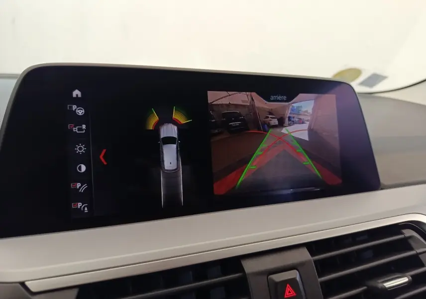 Écran de la BMW X3 gris clair 2020 montrant la caméra de recul et l'aide au stationnement en vue intérieure.