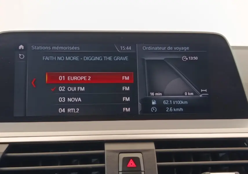 Écran central de navigation et radio d'une BMW X3 gris clair, affichant stations FM et ordinateur de bord.