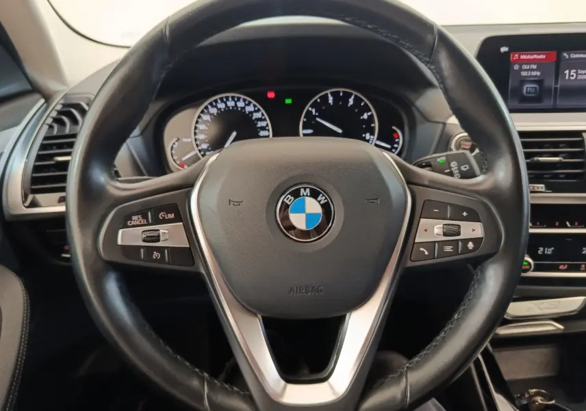 Vue rapprochée du volant cuir et alu multifonctions d’un BMW X3 2020 avec tableau de bord et écran central visibles.