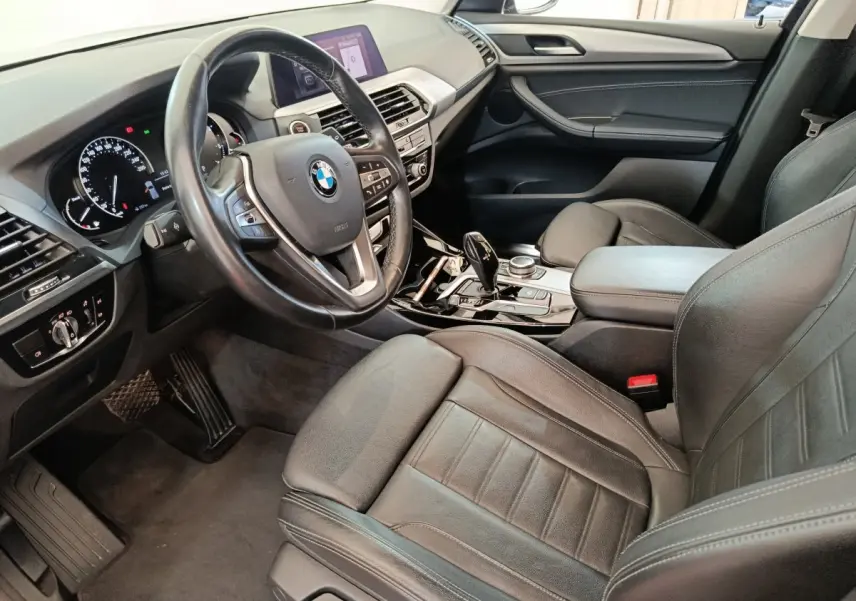 Intérieur BMW X3 xDrive20d 2020 vu côté conducteur, sièges cuir noirs et volant multifonctions alu-cuir.