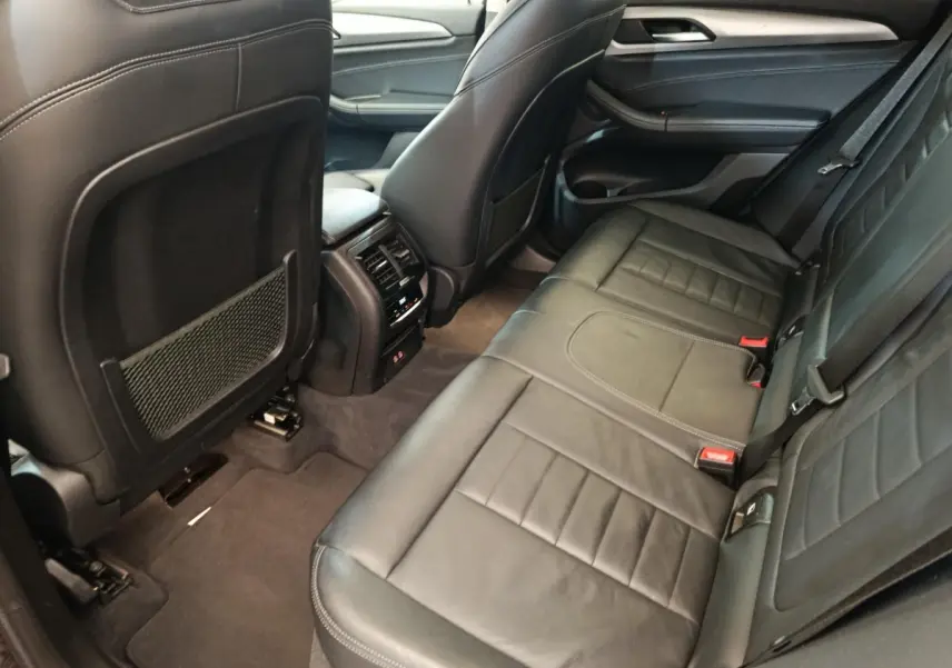 Vue intérieure côté droit des sièges arrière en cuir noir du BMW X3 xDrive20d 2020 avec console centrale et aérateurs.